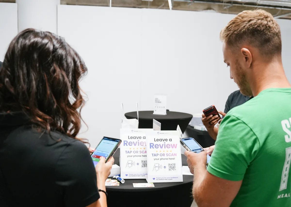 People using their phones beside Review Canopy QR and NFC review stands